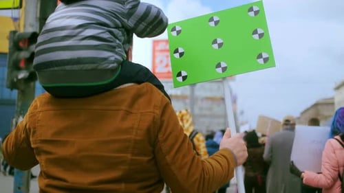Man with Child at Protest Holds Chroma Key Sign