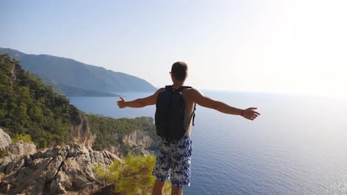 Male Hiker Standing on Peak and Victoriously Raising Hands Rejoicing Achievement or Success. Man