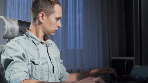 Man Types at Computer Keyboard Late at Night