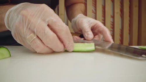Male Cook Hands in Gloves Cutting Cucumbers on Table Close Up