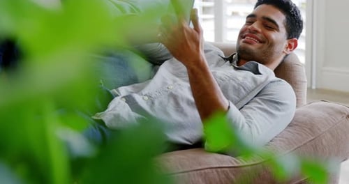 Happy man using mobile phone in living room