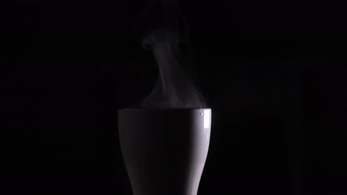 Dampf aus einer weißen Tasse mit kochendem Wasser. Aus einer Tasse heißen Kaffees steigt ein Rinnsal Dampf auf
.