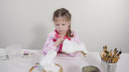 Time lapse. Little girl painting paper mache figurine at homeschooling art class.