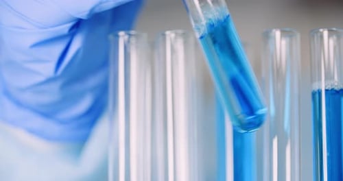 Gloved Hand Holding Test Tube with Blue Liquid