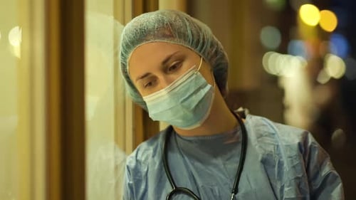 Sad Female Doctor or Nurse Feeling Down Near Hospital at Night