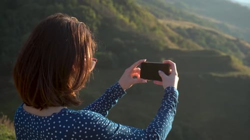 Woman Taking Photo of Mountain View With Phone