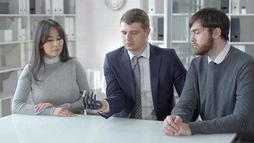 Businessman with Prosthetic Hand Discussing Holographic Globe with Colleagues