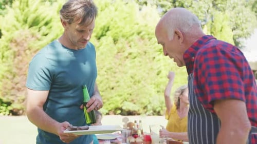 Happy caucasian family having barbecue and eating in garden