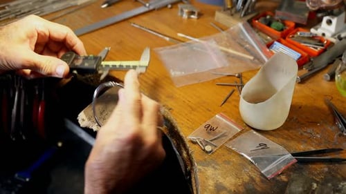 Craftsman Measuring a Bracelet With Caliper on Workbench