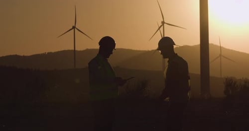 Engineers Discussing Wind Turbines at Sunset