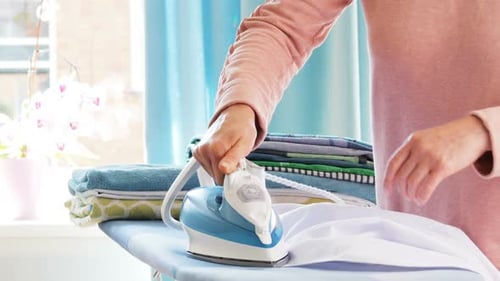 Person Ironing White Shirt on Ironing Board