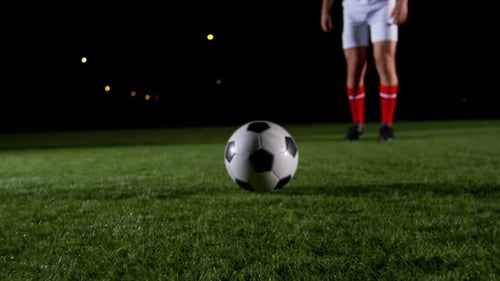 Soccer Player Kicks Ball at Night