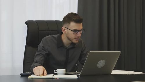 Mann schaut auf Laptop-Bildschirm, tippt auf der Tastatur und macht sich Notizen. Unternehmenskonzept