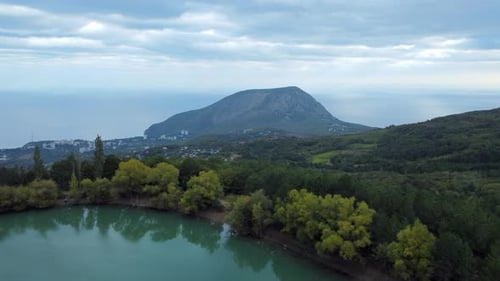 Aerial footage over a green lake with a beautiful sleeping bear mountain
