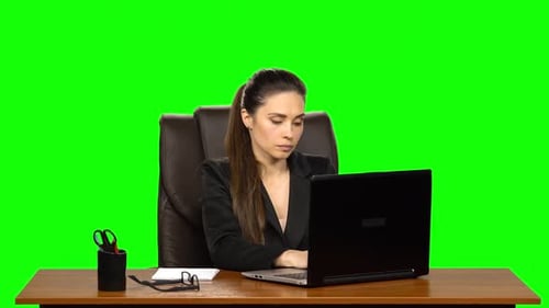 Female Manager Works on a Laptop and Takes Notes. Green Screen Background