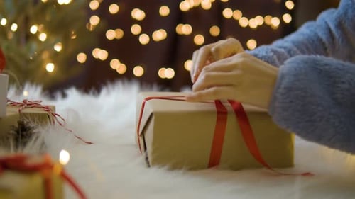 Hands Tying Red Ribbon on Christmas Gift