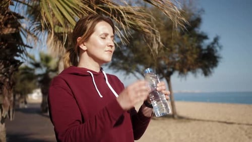 Woman Drinking Water at a Tropical Beach