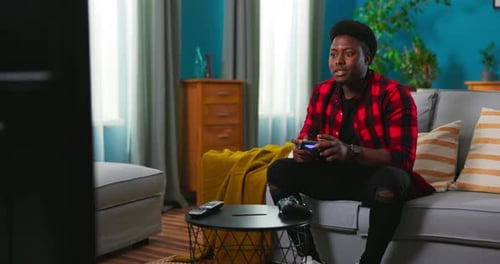 Young Man Plays Video Game on Couch at Home