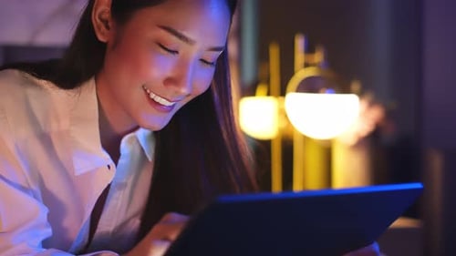 Young Asian beautiful woman enjoy using smartphone in bedroom at night time.