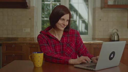 Woman Working on Laptop at Kitchen Table