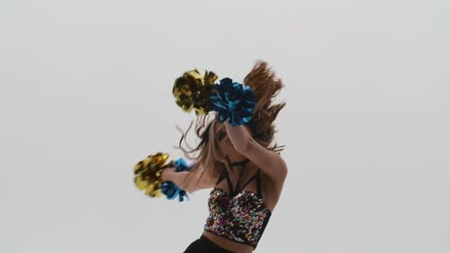 Silhouette of Slender Cheerleader in Shiny Top and Leggings Dancing Energetically with Pompoms in