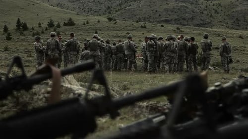 Schwenken, Ausrüstung im Vordergrund, eine Gruppe von Soldaten im Hintergrund im Fokus.