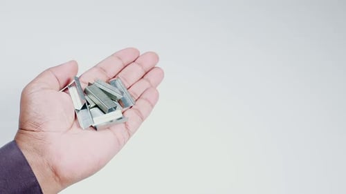 Hand Holds Metal Staples Off Center