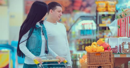 Father Mother and Little Daughter Picking Peanuts in a Package in a Supermarket
