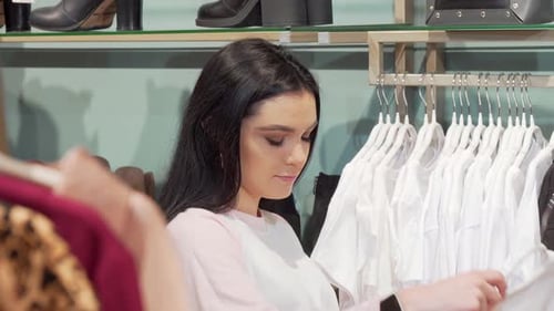 Woman Browsing Clothing Rack in Fashion Store
