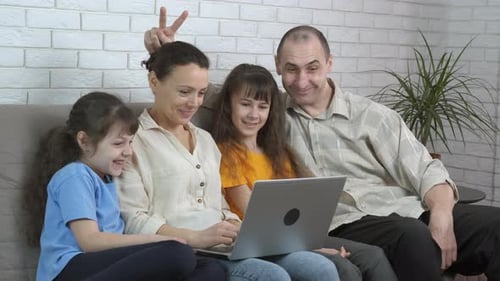 Happy Family on Couch Using Laptop