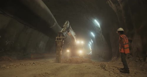 Construction workers supervising heavy machinery during tunnel construction work