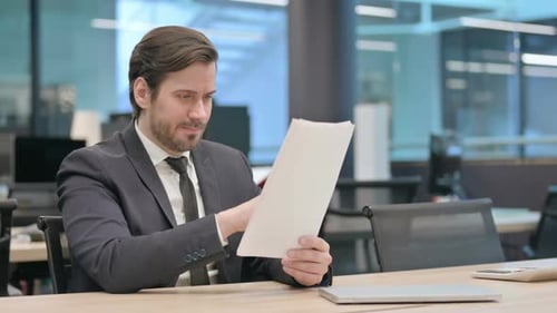 Upset Businessman Reading Documents in Office