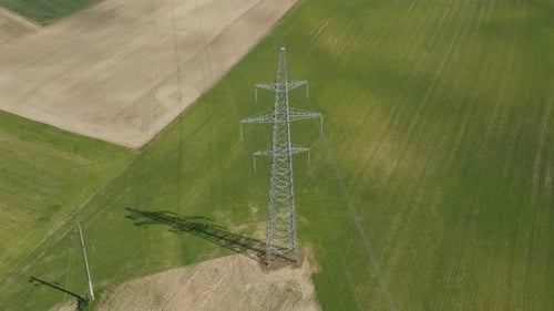 Electrical Tower Amidst Green and Brown Fields