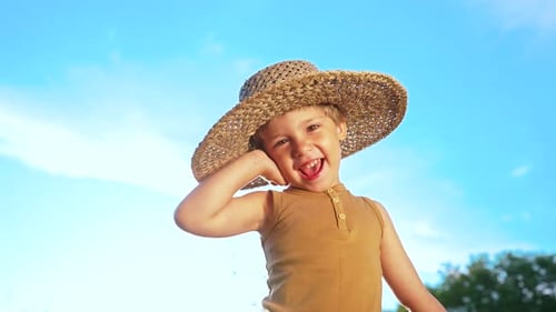 Laughing Child in Oversized Hat Smiles Outdoors