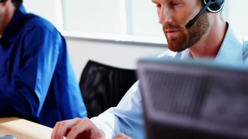 Männliche Führungskraft mit Headset arbeitet am Computer