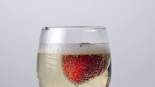 Close-up View of Strawberry Falling Into a Glass of Champagne on a White Background
