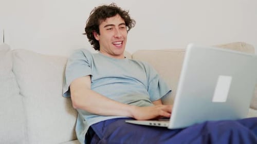 Young Adult Relaxing on Couch Using Laptop