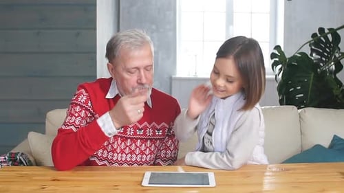 Grandfather and Granddaughter Play on Tablet Indoors