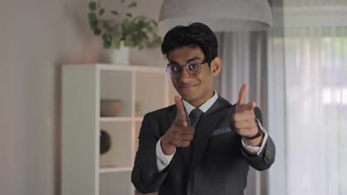 Smiling Man Gesturing with Finger Guns Indoors