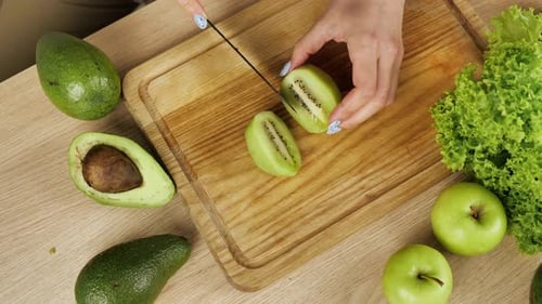 Woman Slicing Kiwi Fruit on Cutting Board