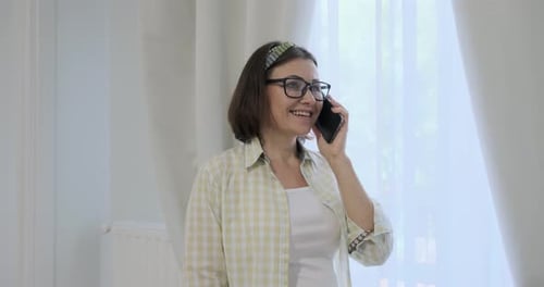 Woman Smiling Talking on Smartphone Indoors by Window