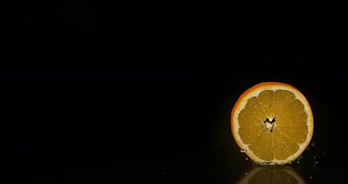 Orange Slice Rotating on Black Reflective Surface