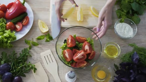 Hands of Woman Zitrone in Läppchen schneiden und Saft in Salatschüssel pressen