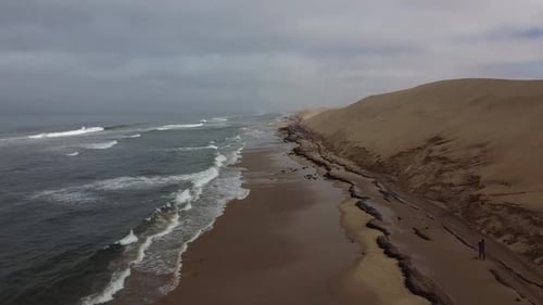 Stunning dark wavy ocean and massive sand dunes, Sandwich Harbour, Namibia