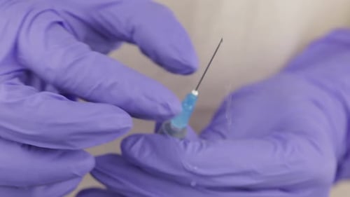 Die Hände des Arztes geben überschüssige Luft aus der Spritze ab und bereiten sich auf die Injektion vor