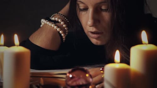 Woman Sits with Candles in Dimly Lit Room