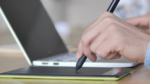 Graphic Designer Using Pen and Tablet at Workplace