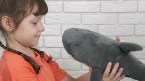 Girl Smiles and Hugs a Plush Shark Toy