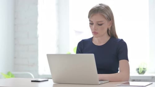 Woman Massaging Neck at Desk in Office