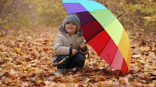 Smiling Little Boy Peeking Out of a Rainbow Umbrella